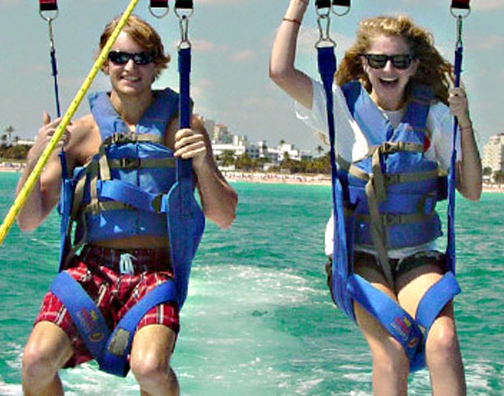two teenagers parasailing over the water